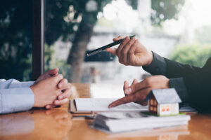 real estate agent holding house key to his client after signing