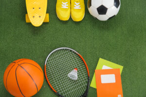 Sport equipment with sneakers and notebooks on color background